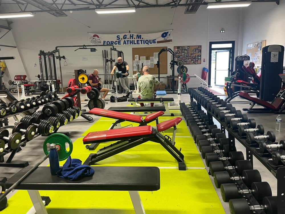 Espace haltères et bancs inclinables de la salle SGHM, banderole SGHM Force Athlétique au fond
